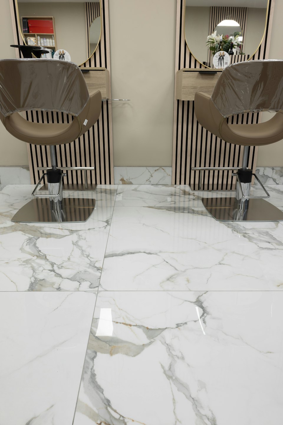 Due moderne poltrone da parrucchiere con specchi a cornice dorata.
