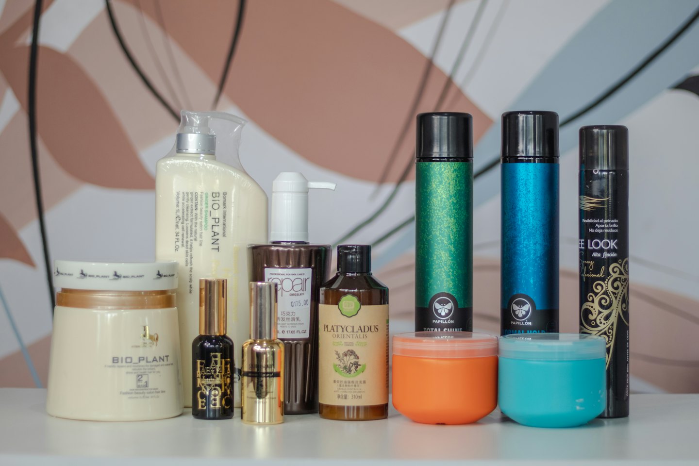 Vari flaconi per la cura dei capelli e prodotti per lo styling disposti su una superficie.