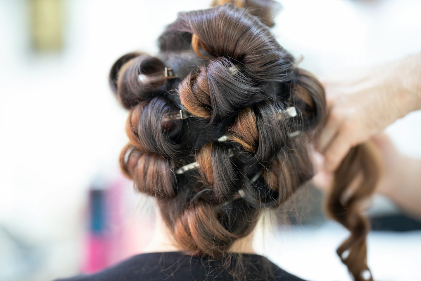 Parrucchiere aggiunge forcine argentate a capelli ricci e schiariti.